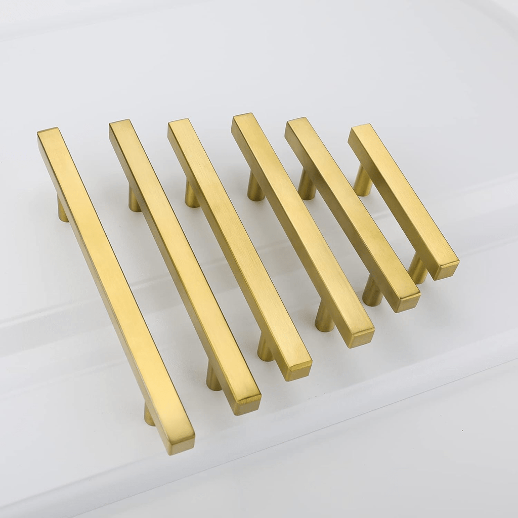 Set of ten goldenwarm brushed‑brass T‑bar cabinet pulls—modern gold hardware handles measuring 7½ in overall with 5 in (128 mm) hole centers—shown mounted on a white shaker‑style kitchen drawer for a sleek, contemporary upgrade.