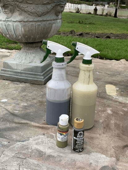 DIY outdoor planter painting supplies including spray bottles filled with paint mixtures and acrylic craft paints set up for creating a weathered stone effect."
