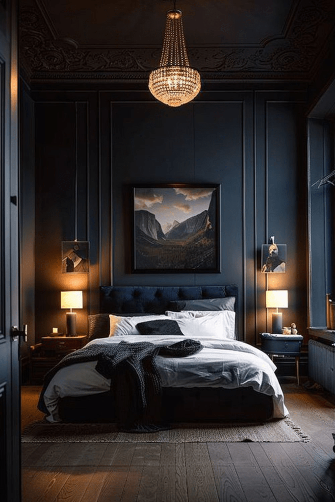 "Moody luxury bedroom with dark navy walls, tufted velvet headboard, and crystal chandelier. Modern interior design featuring layered white bedding, cozy knit throw, bedside lamps, and landscape artwork for a sophisticated and dramatic bedroom retreat."