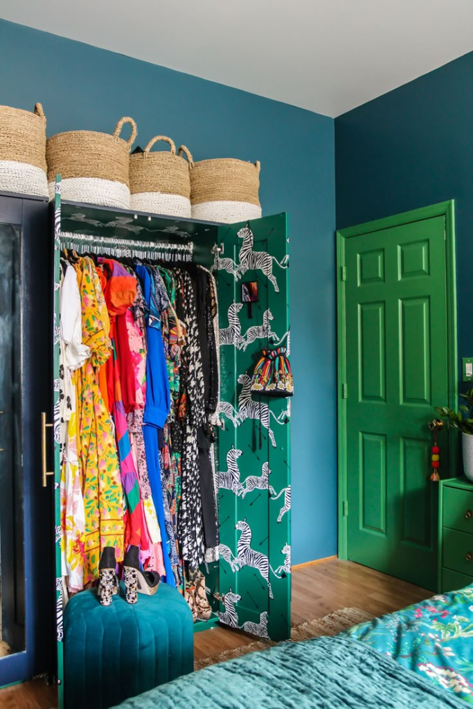 "Colorful eclectic closet with patterned zebra wardrobe, vibrant dresses, and woven storage baskets. Bold bedroom decor featuring green walls, teal accents, and a playful mix of prints for a creative and stylish personal space."