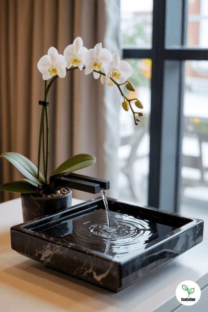 Modern tabletop water fountain with flowing water beside a white orchid plant, creating a calm, minimalist wellness and mindfulness home decor scene.