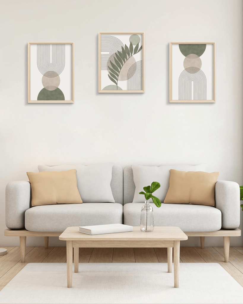 Minimal Scandinavian living room with beige sofa, neutral cushions, light wood coffee table, and botanical abstract wall art, featuring a calm modern home decor aesthetic in soft natural tones.