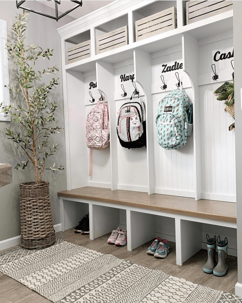 “Built-in mudroom cubbies with bench seating, kids backpack hooks with name labels, shoe storage cubbies, and farmhouse entryway organization.”
